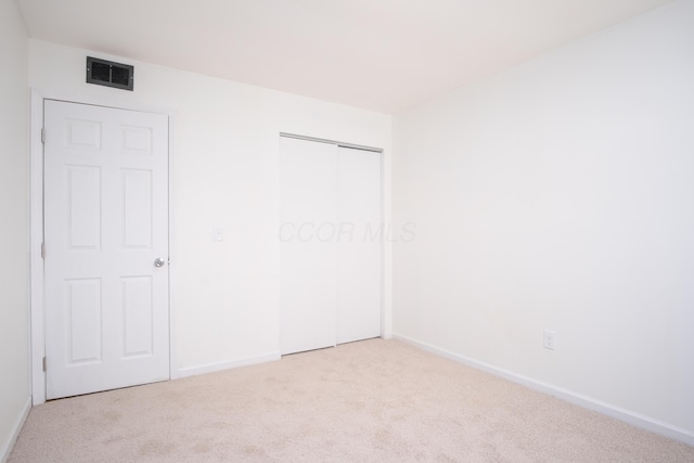 unfurnished bedroom featuring a closet and light carpet