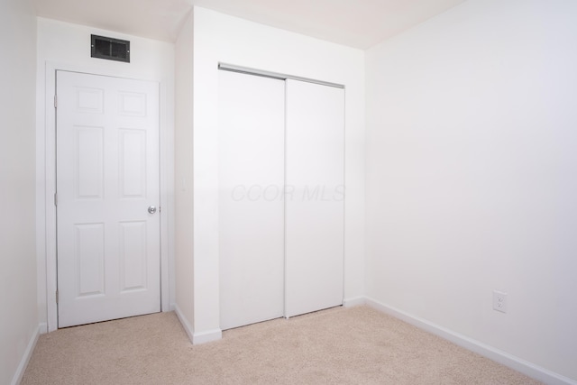 unfurnished bedroom with light colored carpet and a closet