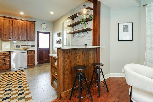 kitchen featuring a kitchen breakfast bar, dishwasher, and backsplash