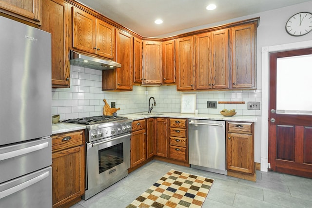 kitchen with tasteful backsplash, appliances with stainless steel finishes, sink, and light tile patterned floors