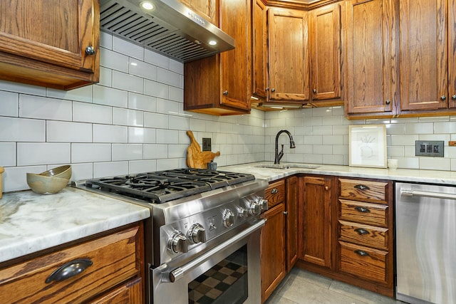 kitchen with light tile patterned flooring, tasteful backsplash, ventilation hood, appliances with stainless steel finishes, and light stone countertops