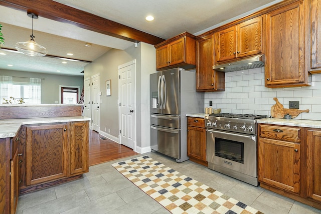 kitchen with appliances with stainless steel finishes, decorative backsplash, hanging light fixtures, light tile patterned floors, and beam ceiling