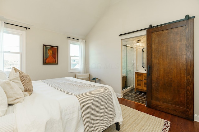 bedroom with vaulted ceiling, a barn door, ensuite bathroom, and dark hardwood / wood-style flooring