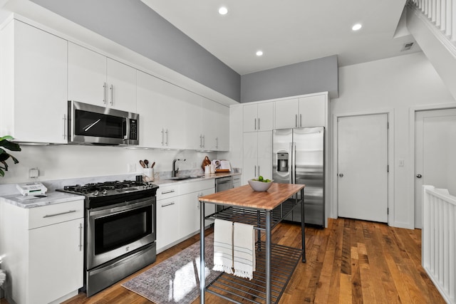 kitchen featuring appliances with stainless steel finishes, dark wood-type flooring, sink, and white cabinets