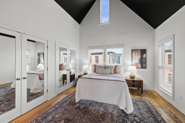 bedroom with french doors, two closets, multiple windows, and hardwood / wood-style flooring