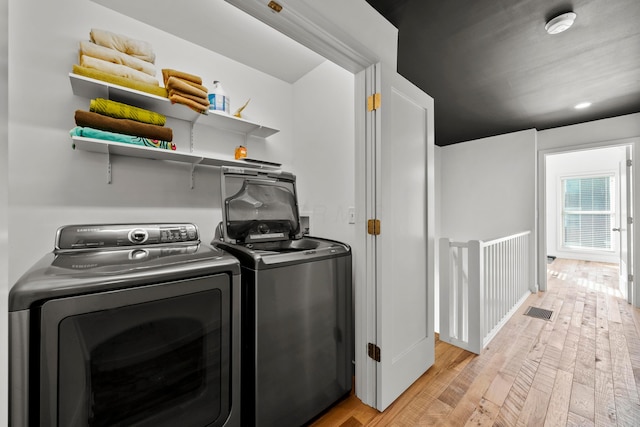 laundry room featuring washer and clothes dryer and light wood-type flooring