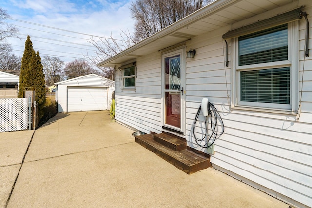 view of property exterior with entry steps, a detached garage, concrete driveway, and an outdoor structure