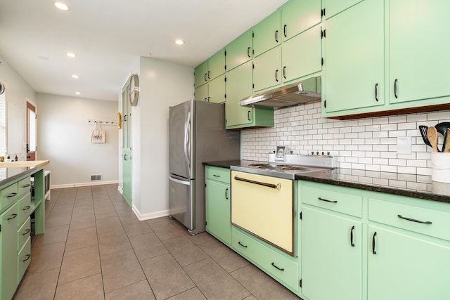 kitchen with under cabinet range hood, freestanding refrigerator, tasteful backsplash, white range with electric cooktop, and dark countertops