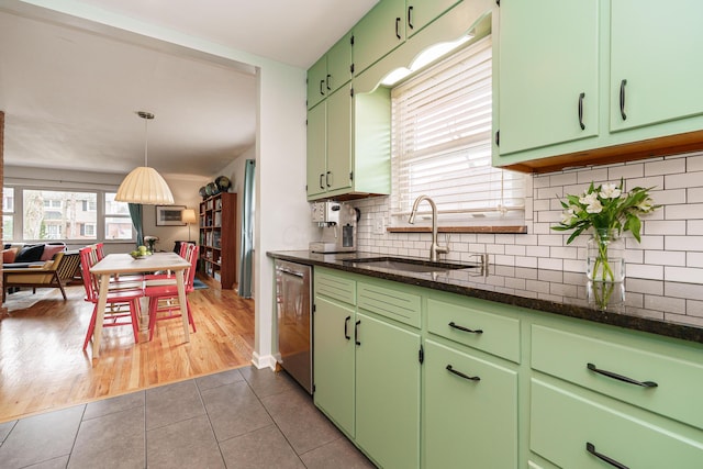 kitchen with tasteful backsplash, a sink, dark stone counters, dishwasher, and dark tile patterned floors