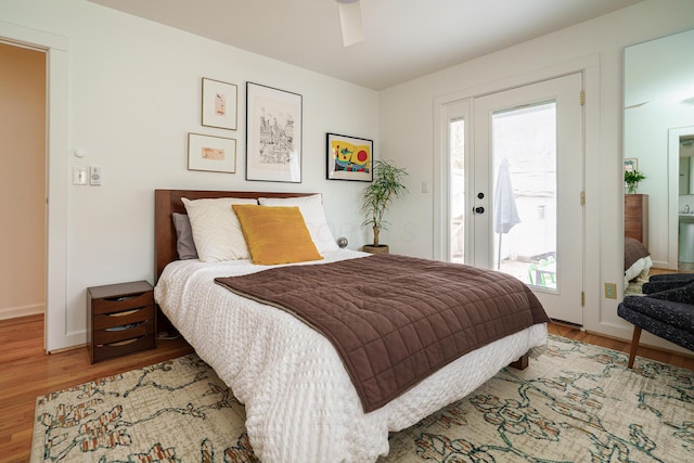 bedroom featuring access to exterior, baseboards, and wood finished floors