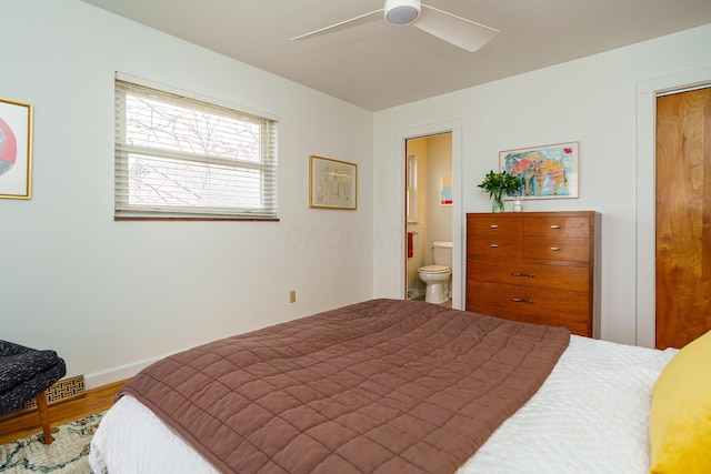 bedroom featuring ensuite bath, baseboards, ceiling fan, and wood finished floors