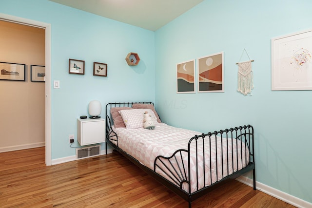 bedroom with wood finished floors, visible vents, and baseboards