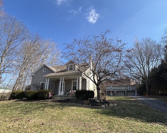 view of front facade featuring covered porch, driveway, and a front yard