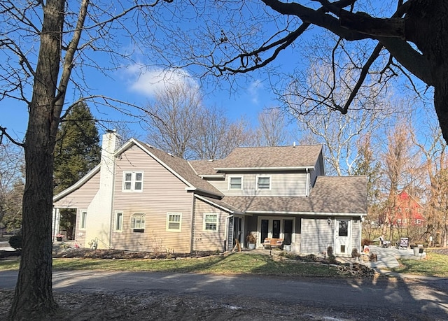 traditional-style house with roof with shingles and a chimney