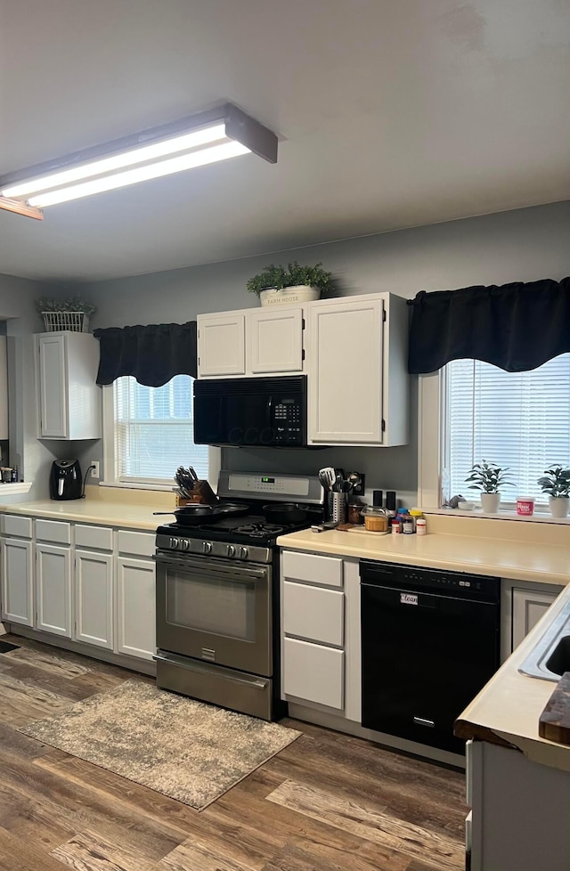 kitchen with dark wood-style floors, black appliances, light countertops, and white cabinetry