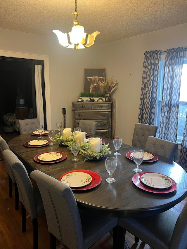 dining room with a textured ceiling, wood finished floors, and an inviting chandelier