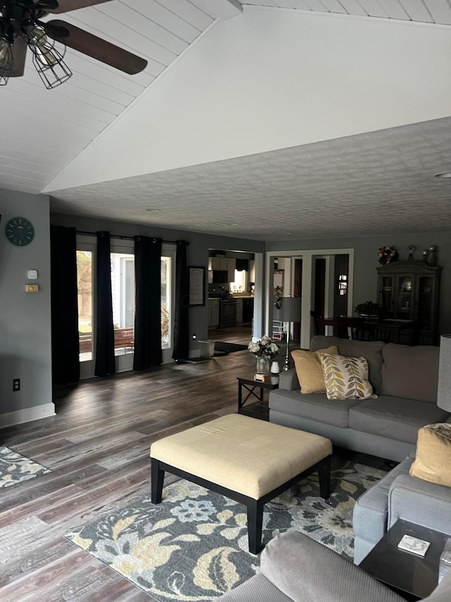 living room featuring lofted ceiling, ceiling fan, baseboards, and wood finished floors