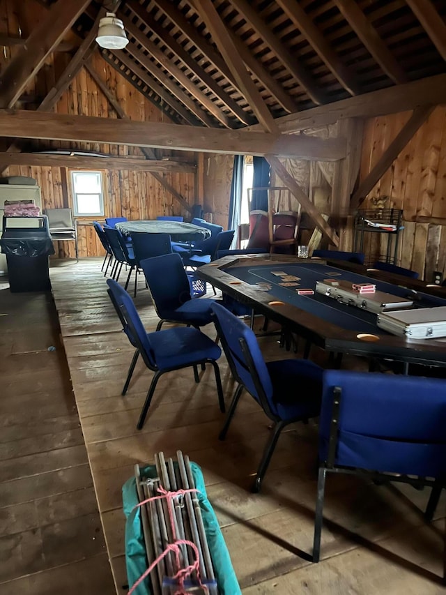 interior space with vaulted ceiling, wood finished floors, and wooden walls