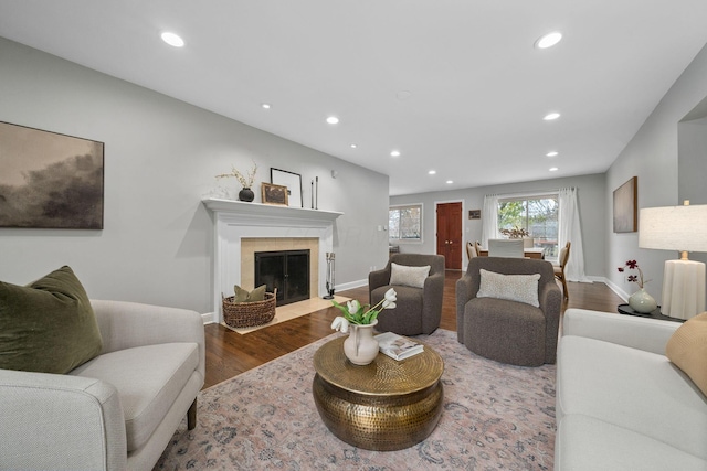 living room featuring a fireplace with flush hearth, baseboards, wood finished floors, and recessed lighting