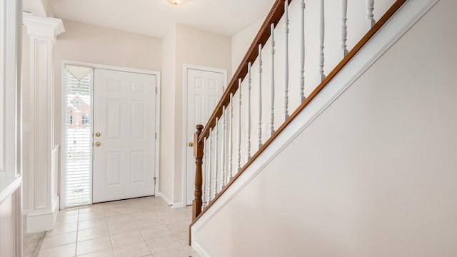 entrance foyer featuring light tile patterned floors, decorative columns, stairs, and baseboards