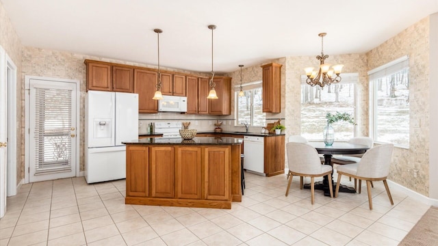 kitchen with a center island, decorative light fixtures, brown cabinetry, a chandelier, and white appliances