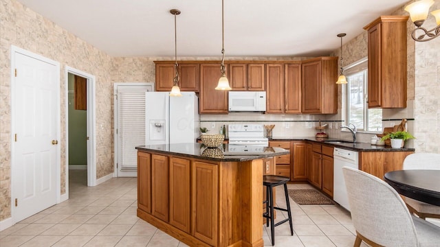 kitchen with pendant lighting, brown cabinetry, a kitchen island, a sink, and white appliances