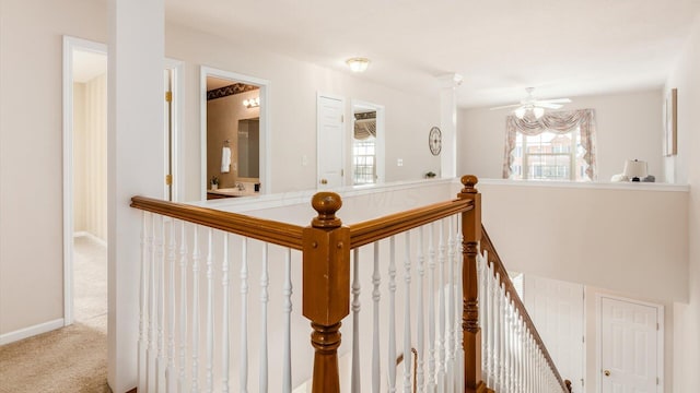 hall with light carpet, an upstairs landing, and baseboards