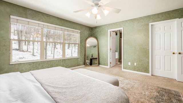 carpeted bedroom featuring arched walkways, ceiling fan, ensuite bath, and baseboards