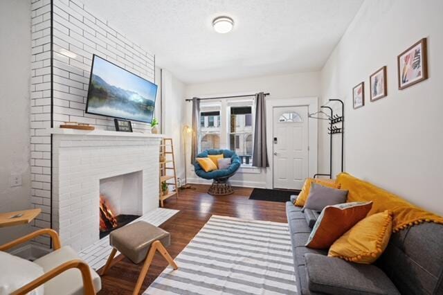 living room featuring dark wood-type flooring and a brick fireplace