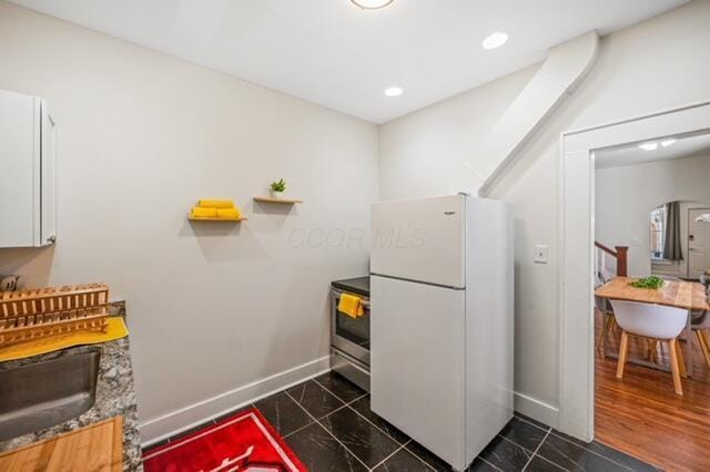 kitchen featuring sink, white cabinets, white refrigerator, dark tile patterned floors, and electric range