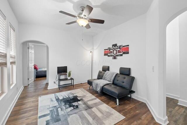 living area featuring dark wood-type flooring and ceiling fan