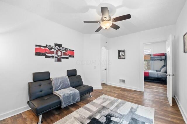 living area featuring dark wood-type flooring and ceiling fan