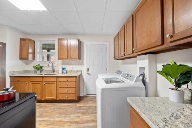 laundry room with sink, light hardwood / wood-style flooring, and washer and dryer