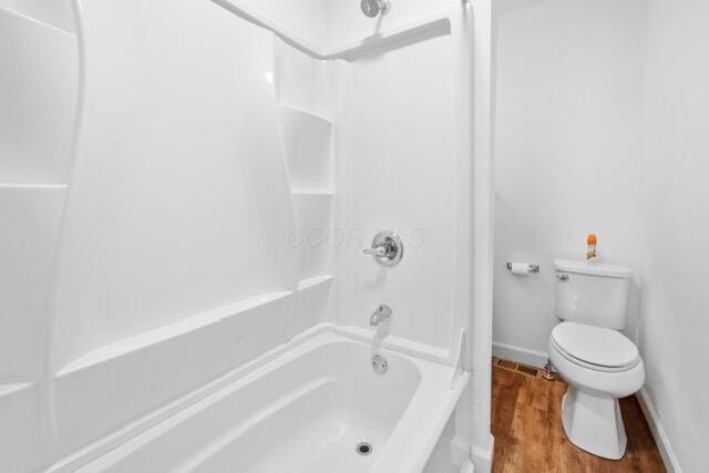 bathroom featuring hardwood / wood-style flooring, bathtub / shower combination, and toilet