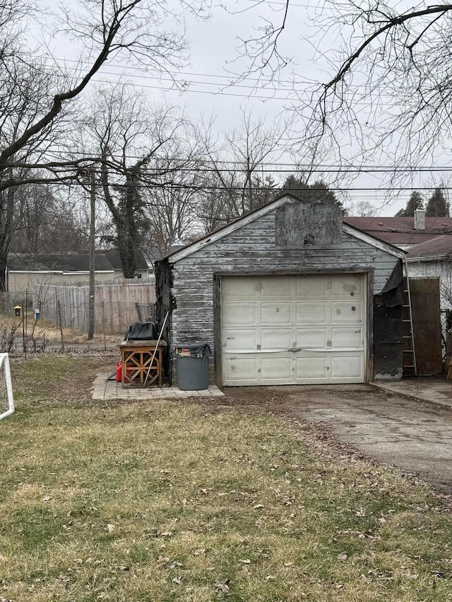 detached garage featuring driveway and fence