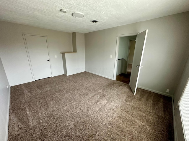 unfurnished bedroom featuring a closet, a textured ceiling, and dark colored carpet