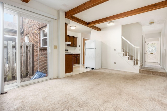 unfurnished living room with beam ceiling and light colored carpet