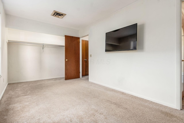 unfurnished bedroom featuring light carpet and a closet