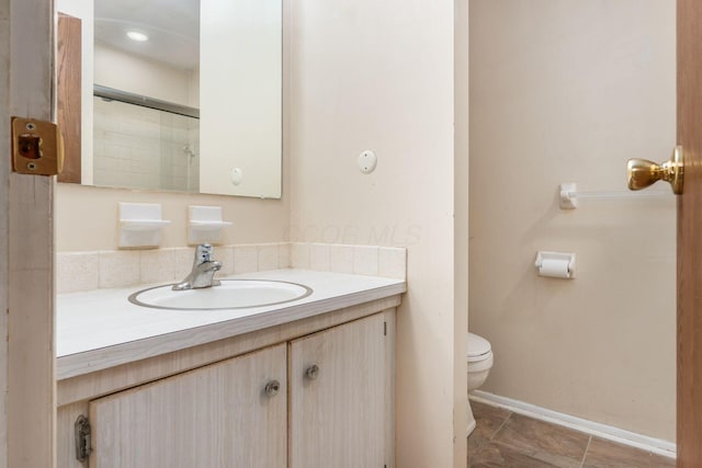 bathroom with vanity, toilet, and a shower with door