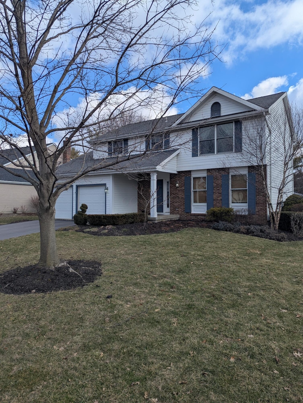 view of front of home with brick siding, an attached garage, and a front yard