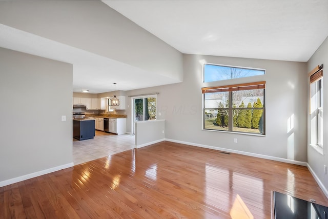 unfurnished living room featuring lofted ceiling, light wood-style flooring, and baseboards