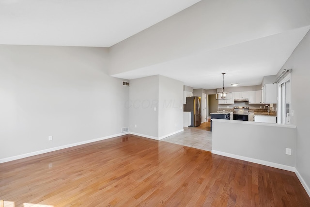 unfurnished living room with light wood-type flooring, baseboards, and visible vents