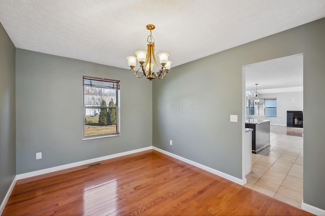 spare room featuring a wealth of natural light, light wood-style flooring, and an inviting chandelier