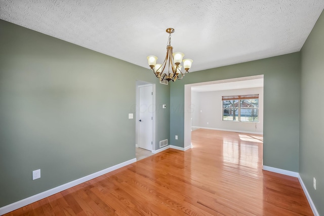 unfurnished dining area with light wood finished floors, visible vents, baseboards, and an inviting chandelier