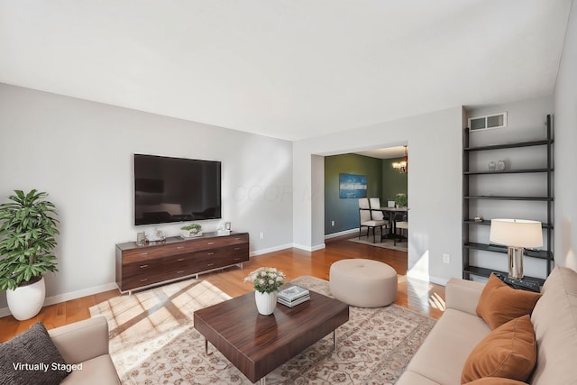 living room with visible vents, baseboards, and wood finished floors