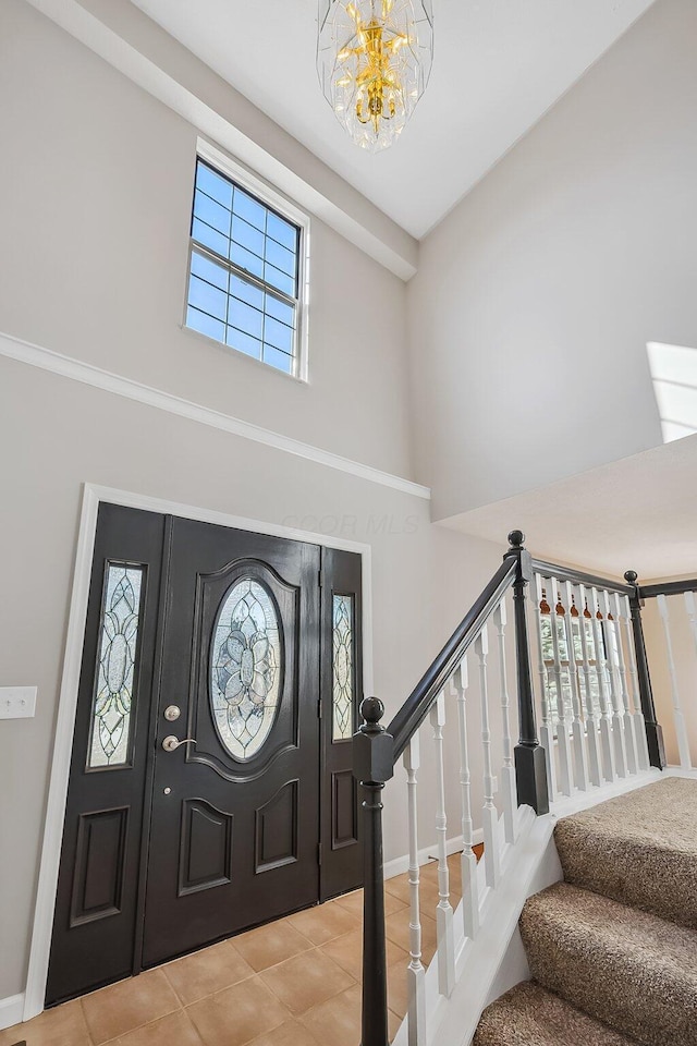 tiled entrance foyer with baseboards, a high ceiling, stairway, and an inviting chandelier