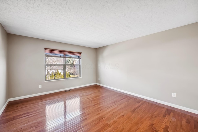 empty room featuring a textured ceiling, light wood-style flooring, and baseboards