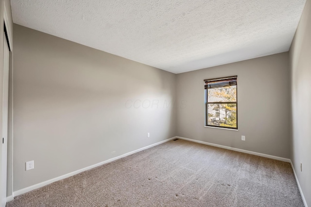 spare room featuring a textured ceiling, baseboards, and carpet flooring