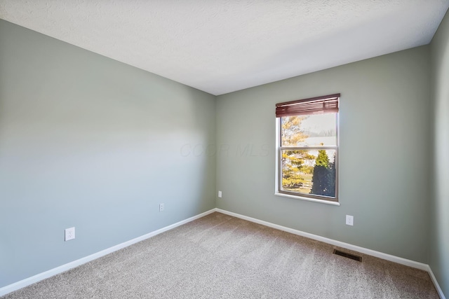 empty room featuring carpet, baseboards, visible vents, and a textured ceiling