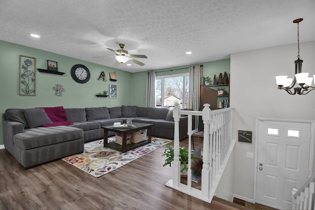 living room featuring ceiling fan with notable chandelier, a textured ceiling, and dark hardwood / wood-style flooring